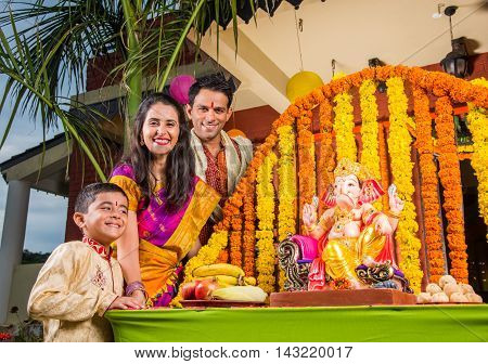 cheerful indian  family welcoming lord Ganesha idol on ganesh festival or ganesh chaturthi on palkhi decorated with garland flowers