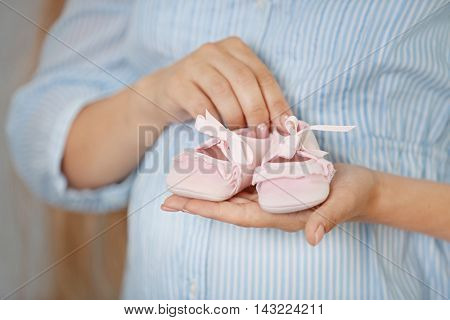 Pregnant woman with baby bootees at home