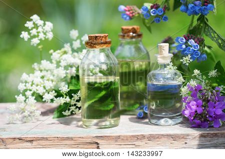 Essential aroma oil in bottles on wooden background outdoor. Selective focus. Natural ogranic products.