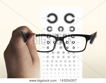 Eyeglasses in hand for eyesight. On the background of a chart test for eyes of Landolt C isolated