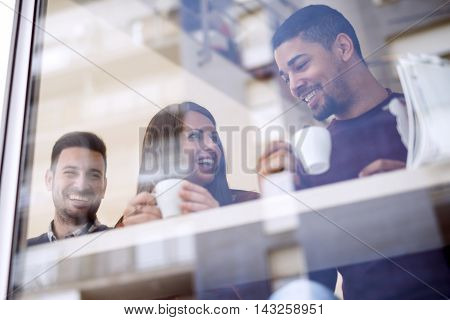 Friends smiling and sitting in a coffee shoptalking and drinking coffee.