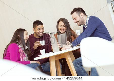 Friends smiling and sitting in a coffee shoptalking and drinking coffee.They are having a great time in cafe.