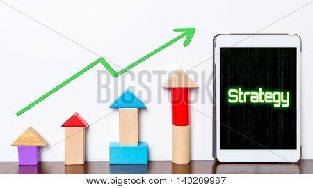 Strategy Business success growing concept on tablet. Toy block rise with Strategy planning stepping up diagram graph. Tablet with hi tech tech text Business strategy success rising up.