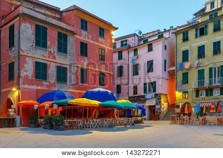 Night fishing village Vernazza with colorful umbrellas and tables on town square, Five lands, Cinque Terre National Park, Liguria, Italy.