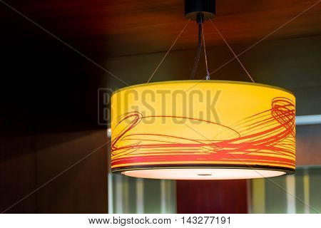 Orange lighting ceiling lamp in dark room.