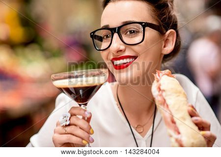 Young woman with shakerato coffee drink and panini with prosciutto outdoor.
