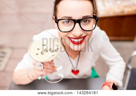 Young woman sitting at the cafe with shakerato drink in cocktail glass outdoor. Traditional italian cold coffee