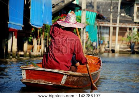 Damnoen Saduak Thailand - January 9 2010: Boatman paddles his tourist boat along a canal at the Damnoen Saduak Floating Market *