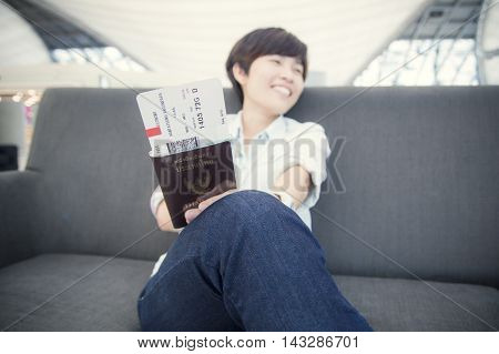 Beautiful Asian woman happy traveller waiting for flight travel at airport terminal
