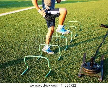 A sprinter exhibits perfect form going over the banana hurdles on a turf field