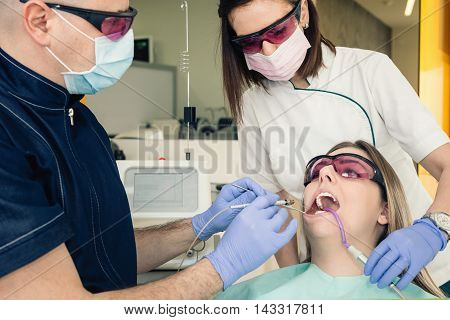 Dental surgery - dentist performing minor laser surgery in patient's mouth