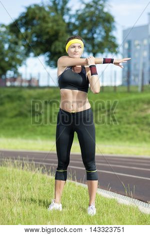 Sport and Fitness Concepts and Ideas. Young Caucasian Female in Athletic Sportgear Having Stretching Excercises Outdoors.Vertical Shot