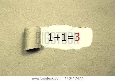 1+1=3 written under torn Brown paper.Business, technology, internet concept.
