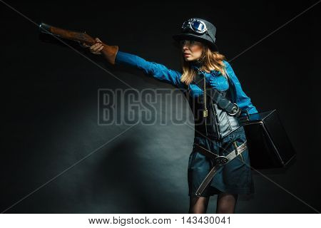 Weapon victorian style vintage concept. Subculture girl in outfit. Steam punk lady with blunderbuss and briefcase aiming for threat.