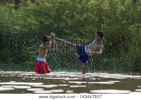 Children are playing Thai boxing in the river.