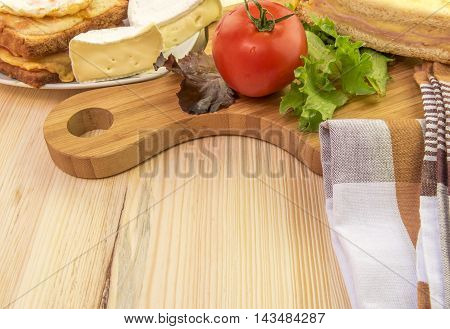 Plate and wooden platter with food - Tasty sandwiches white cheese and some vegetables on a wooden trencher and a plate.
