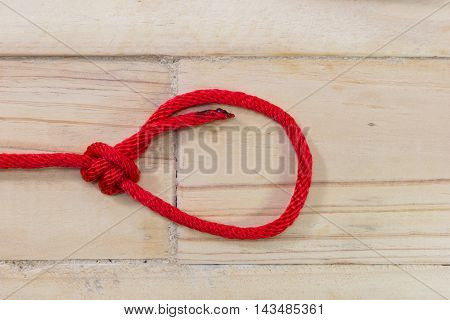 bowline knot made from red synthetic rope tightening on wooden background.