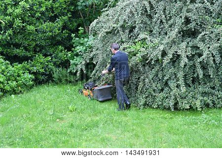 Verneuil sur Seine France - june 27 2016 :a man is cutting lawn in a garden