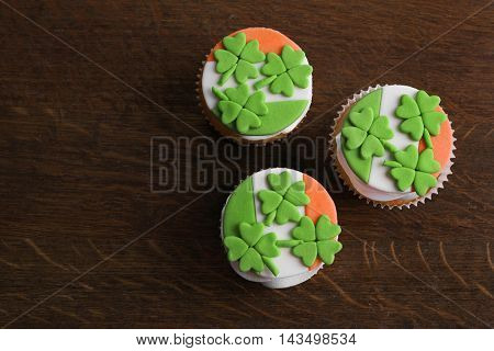 Tasty cupcakes with clover on wooden background. Saint Patrics Day concept