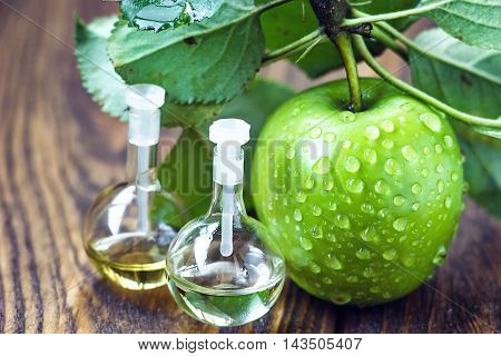 Apple vinegar in glass jar with ripe dreen fruit. Bottle of apple organic vinegar on wooden background. Healthy organic food.