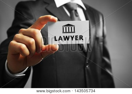 Handsome businessman holding business card LAWYER close up