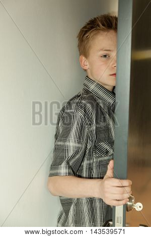 Serious Young Boy Peering Around A Door