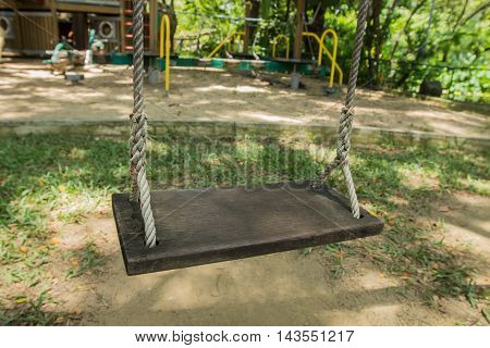 Old wooden vintage garden swing hanging in garden.