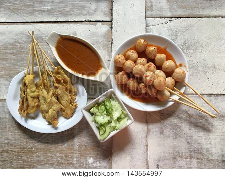 Pork satay dish on a wooden table .