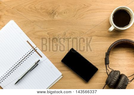 top view of notbook coffee cup smartphone and headphone onwooden background