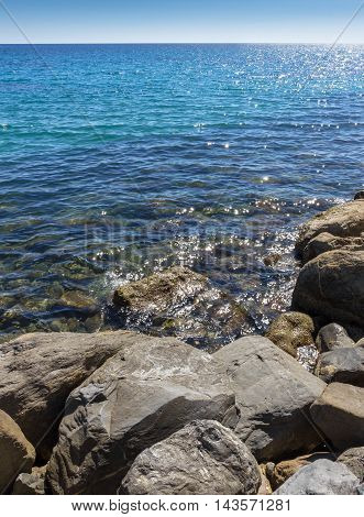 Amazing sea with blue summer wave and rocks. Summer sea background. Endless sea. Daylight sea. Turquoise sea. Sea foam and brown rocks. Sunny day sea view. Sea rock.