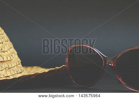 Vintage straw hat and retro sunglasses on background