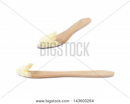 Wooden butterknife with a piece of butter over it, composition isolated over the white background, set of two different foreshortenings