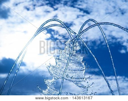 Fountain fresh water splash on hot summer sky background. Clear water or refreshment theme.