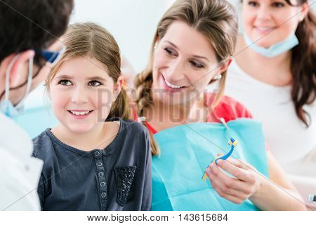 Dentist and his assistant with pregnant woman and child in surgery