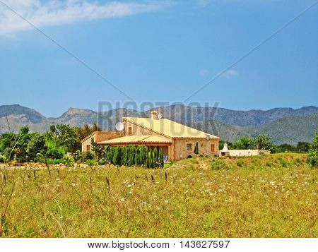 Pollenca Majorca Spain - June 28 2008: Finca vacation rental home with meadow on front surrounded by garden - tramuntana mountains in background