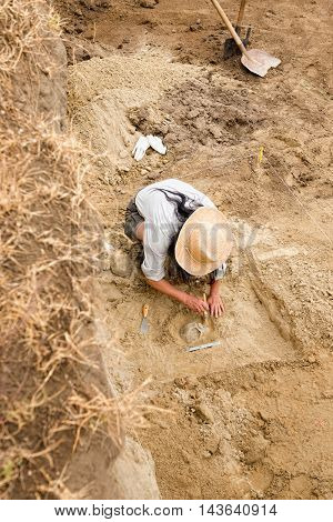Archaeologist Recovering Human Remains From Ancient Grave
