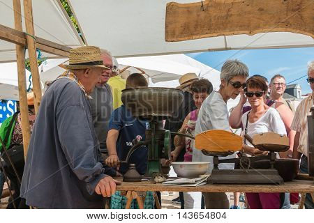 An Old Man Operates An Ancient Machine To Grind Grain