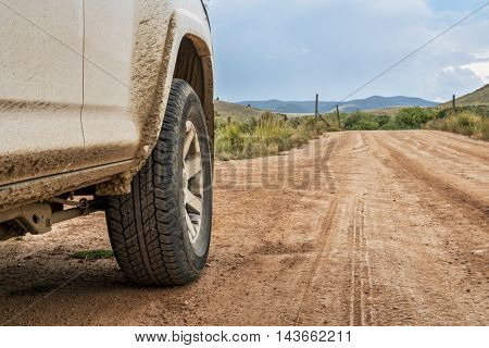 Closeup of 4x4 SUV car driving on a dusty dirt road