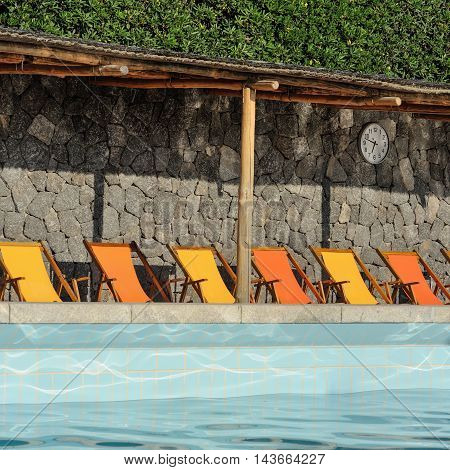 Mediterranean pool with orange and yellow sunbeds in Italy