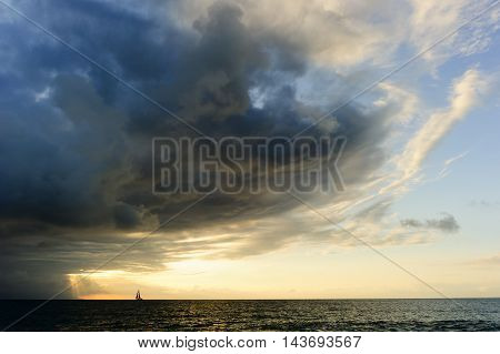Journey is a small boat sailing towards the light of spiritual faith freedom and hope as an approaching surreal storm looms overhead.