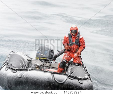 SOUTH GEORGIA, GREAT BRITAIN - NOV 9, 2012:  Unidentified man in a water proof suite in a rubber boat with a motor in the Atlantic Ocean. Atlantic Ocean is the world's second largest ocean