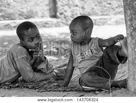 KARA, TOGO - MAR 9, 2013: Unidentified Togolese boys sit near a tree. Children in Togo suffer of poverty due to the unstable econimic situation