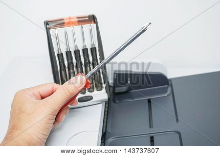 Hold a screwdriver with red handle for printer repair