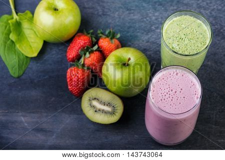 Strawberry and spinash smoothies in glasses with ingredients on dark background selective focus.