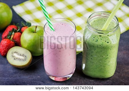 Strawberry and spinash smoothies in glasses with ingredients on dark background selective focus.