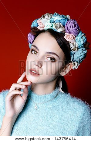 Beautiful model with a wreath of flowers on her head on red background