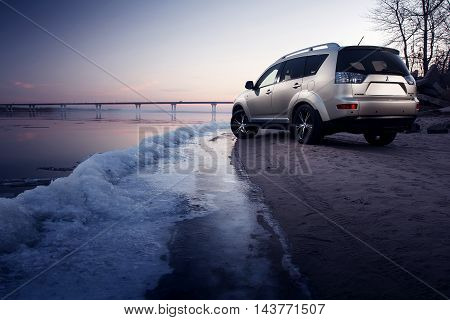 Saratov, Russia - November 27, 2014: Car Mitsubishi Outlander stay on ice coast at winter sunset