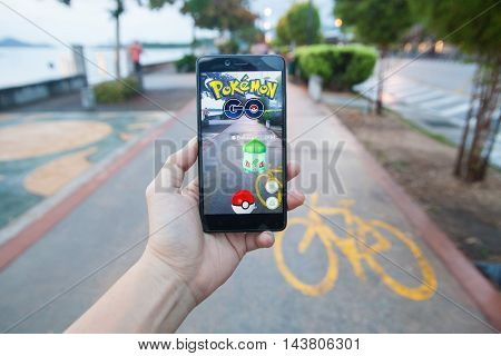 Penang, Malaysia - August 13, 2016 : Man holding a smartphone with his left hand playing Pokemon Go game. Screen on the smartphone is a Pokemon character called 