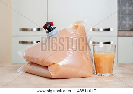 Plastic bag and glass full of apple juice on the wooden table