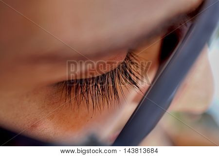 Macro detail of a closed woman eye with extremely long black natural eyelashes and dark brown eyebrows